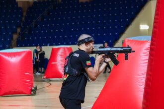Игрок LASERWAR прицеливается из-за красного надувного препятствия